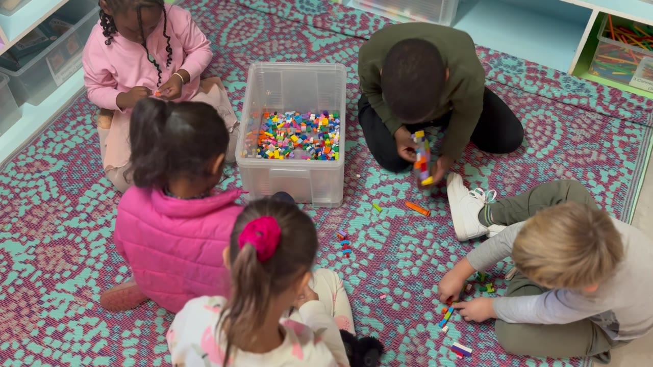 A group of children building together with colourful blocks on the play rug